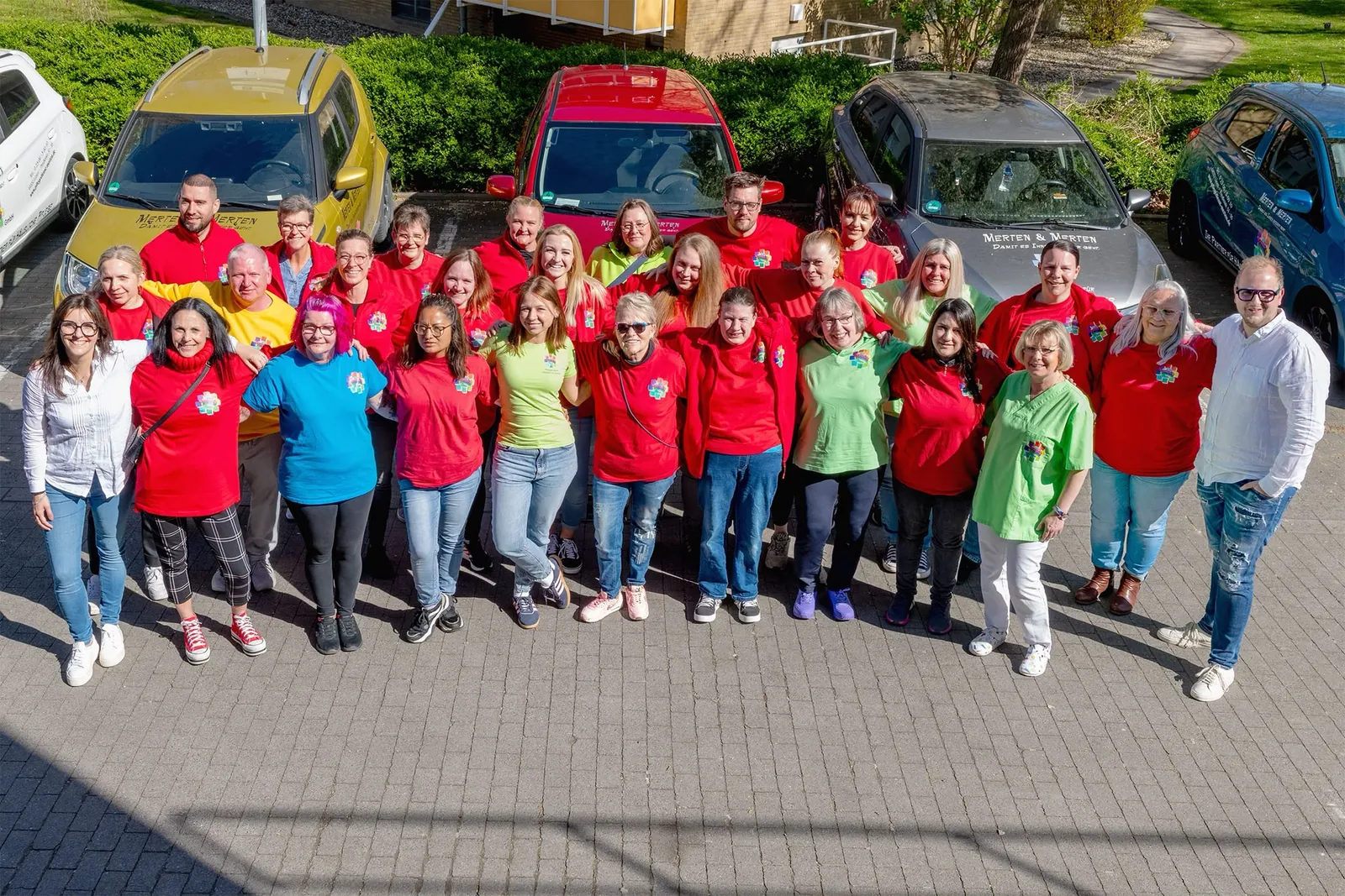 Das Team der Pflegedienst Merten & Merten GmbH beim Teamfoto vor den Dienstwagen